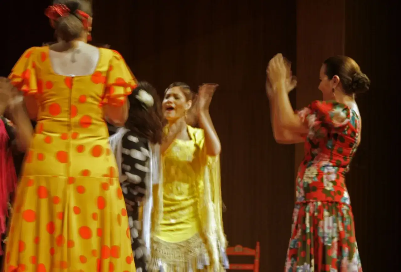 Mujeres bailando rumba flamenco con vestidos vibrantes.