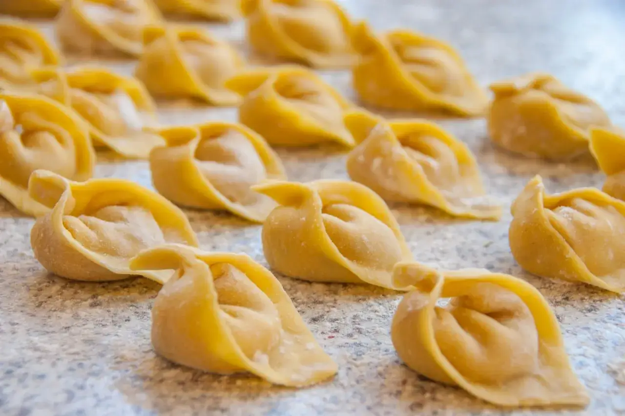 Rządki świeżych, żółtych tortellini na blacie kuchennym, gotowe do gotowania.