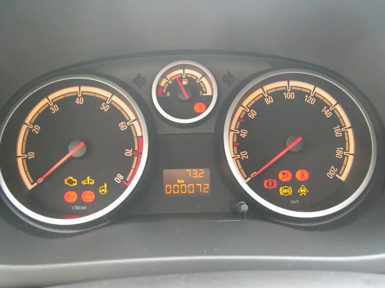 Cruscotto di una Opel Corsa con spie accese: motore, ABS, controllo stabilit&agrave;. Chilometraggio 72 km.