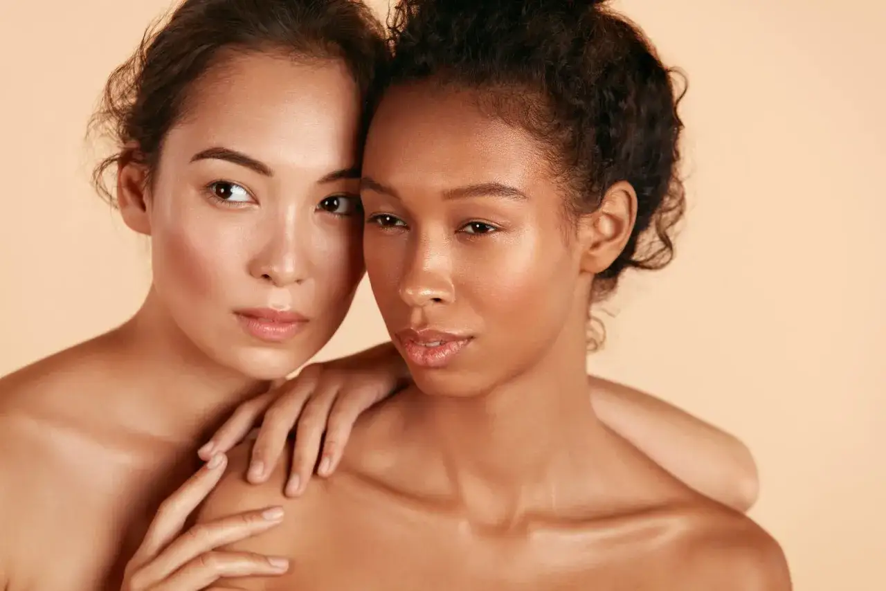 Två kvinnor med vacker hud, en med ljusare hy och en med mörkare. De visar hur man kan kombinera retinol och niacinamide för en strålande hud.