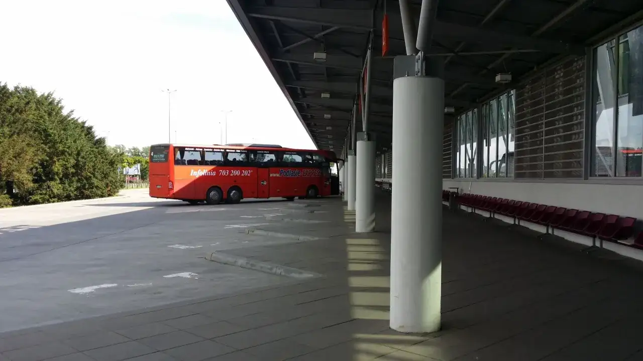 Czerwony autokar Podlasie Express Białystok-Warszawa Okęcie czeka na pasażerów na dworcu.