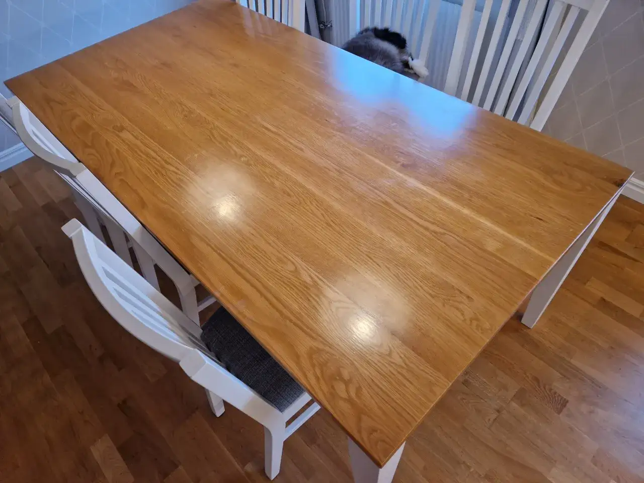 Ett tr&auml;bord med ljus bordsskiva och vita stolar. Kanske dags att m&aring;la bordsskivan f&ouml;r en ny look?
