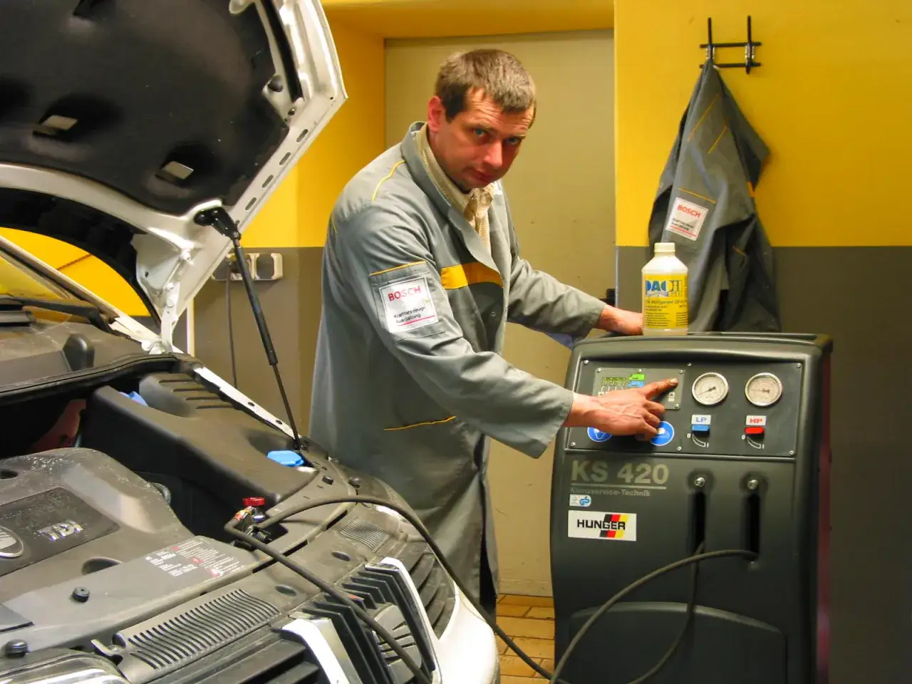 Mechaniker bedient Klimaservicegerät. Die Kosten für die Klimaanlage reparieren sind hier im Blick.