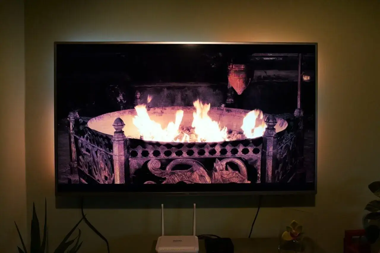 Aplikacja kominek w telewizorze tworzy przytulną atmosferę. Płomienie tańczą w ozdobnym palenisku.