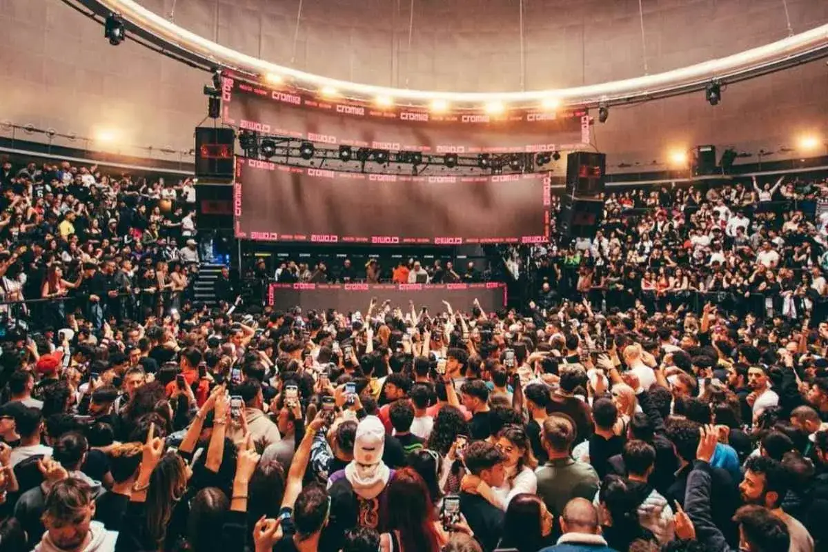 Folla in delirio a un concerto, con schermi giganti e luci. Le recensioni del sound department sono positive!