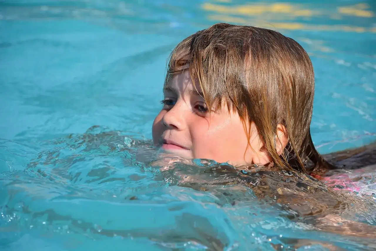 Ein Kind mit nassen Haaren planscht im Wasser. Ein fr&ouml;hlicher Moment beim Monbijou Bad.