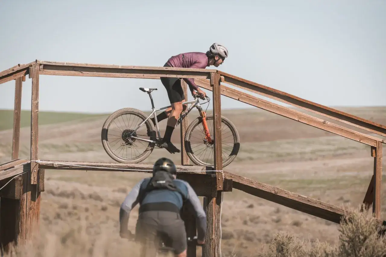 Two cyclists race on a wooden ramp, enjoying the thrill of cross country biking.