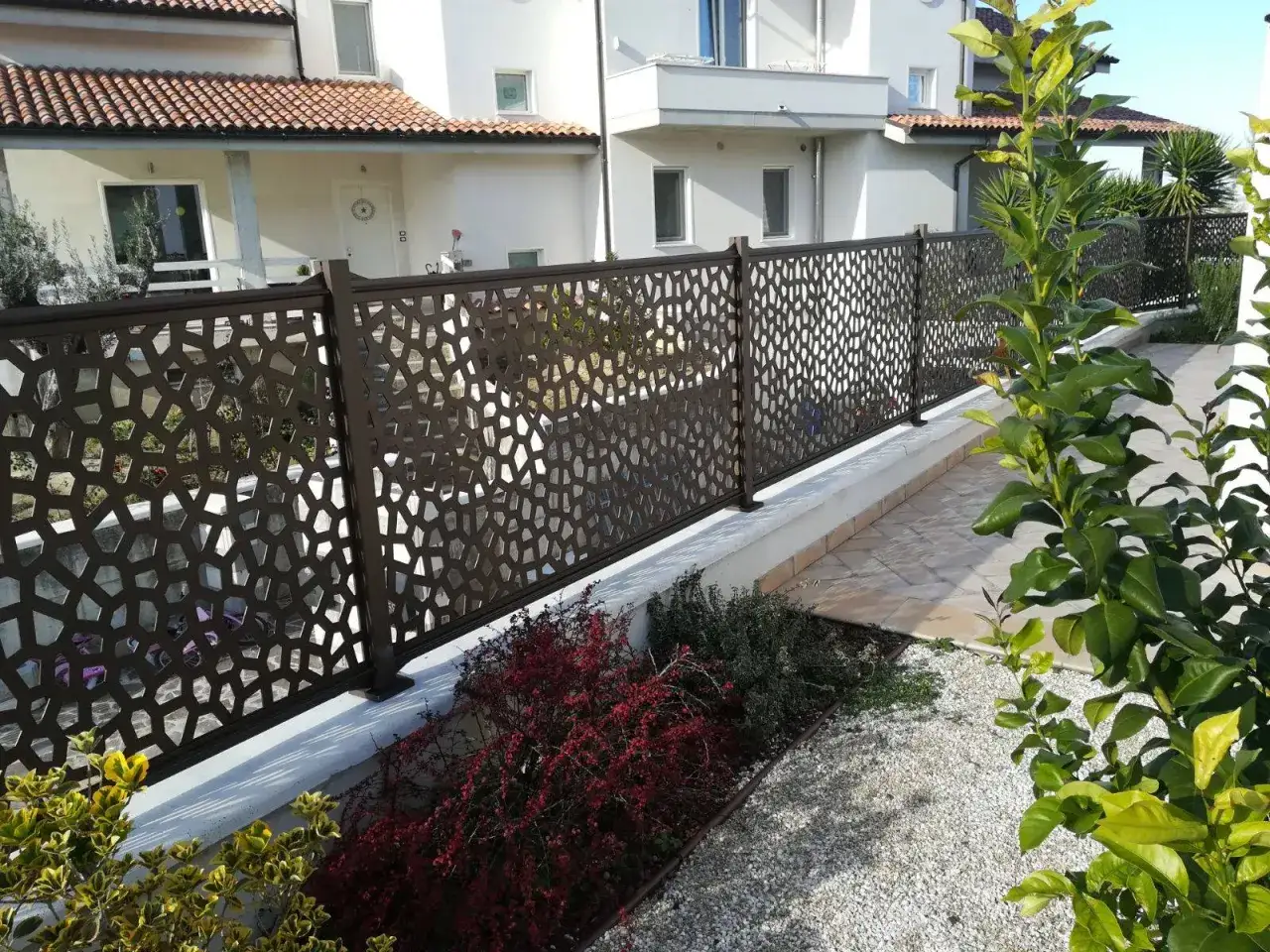 Modern metal fence with geometric cutouts, offering privacy and style. Perfect for **ideas ocultaci&oacute;n jardin** that blend aesthetics and function.