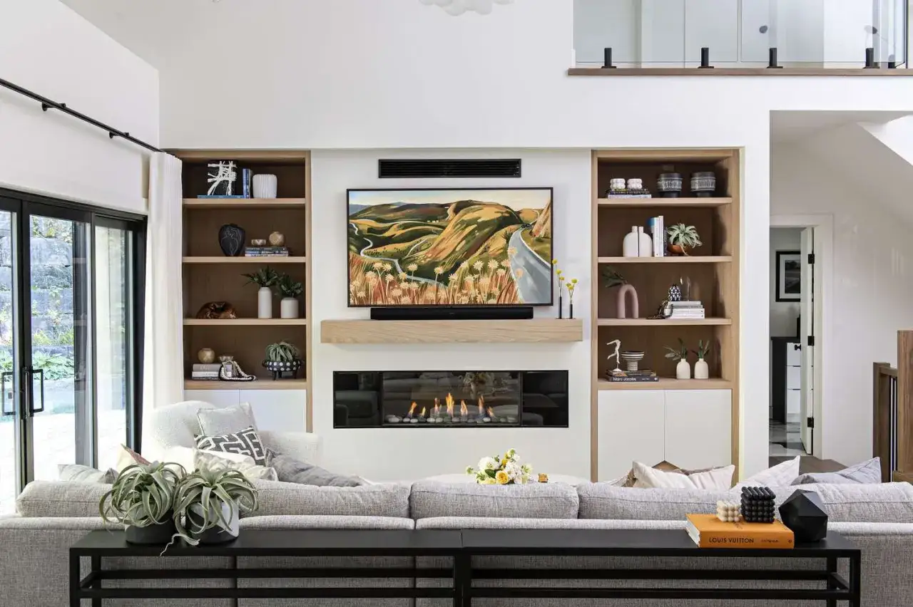 Aménagement salon TV moderne avec cheminée, étagères murales et canapé confortable.