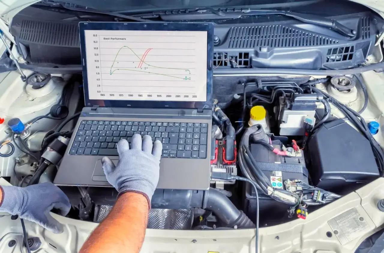 Mechanik diagnozuje problem z samochodem, analizując wykres na laptopie. To może pom&oacute;c zrozumieć, co oznacza kontrolka silnika.