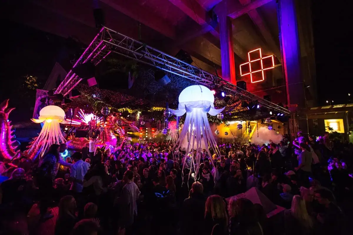 En livlig folkmassa njuter av stockholm nightlife under gigantiska uppbl&aring;sbara maneter och f&auml;rgstark belysning.