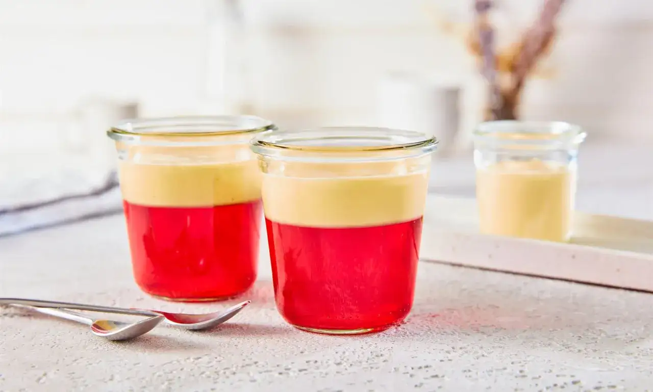 Zwei Gl&auml;ser mit rotem Wackelpudding und Vanillecreme. Perfekt, um Wackelpudding selber machen zu lernen und zu genie&szlig;en.