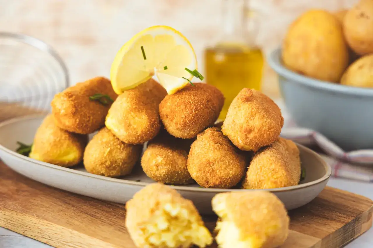 Goldbraune, knusprige Kroketten, frisch zubereitet, mit Zitrone und Kräutern garniert. Perfekt zum Selbermachen!