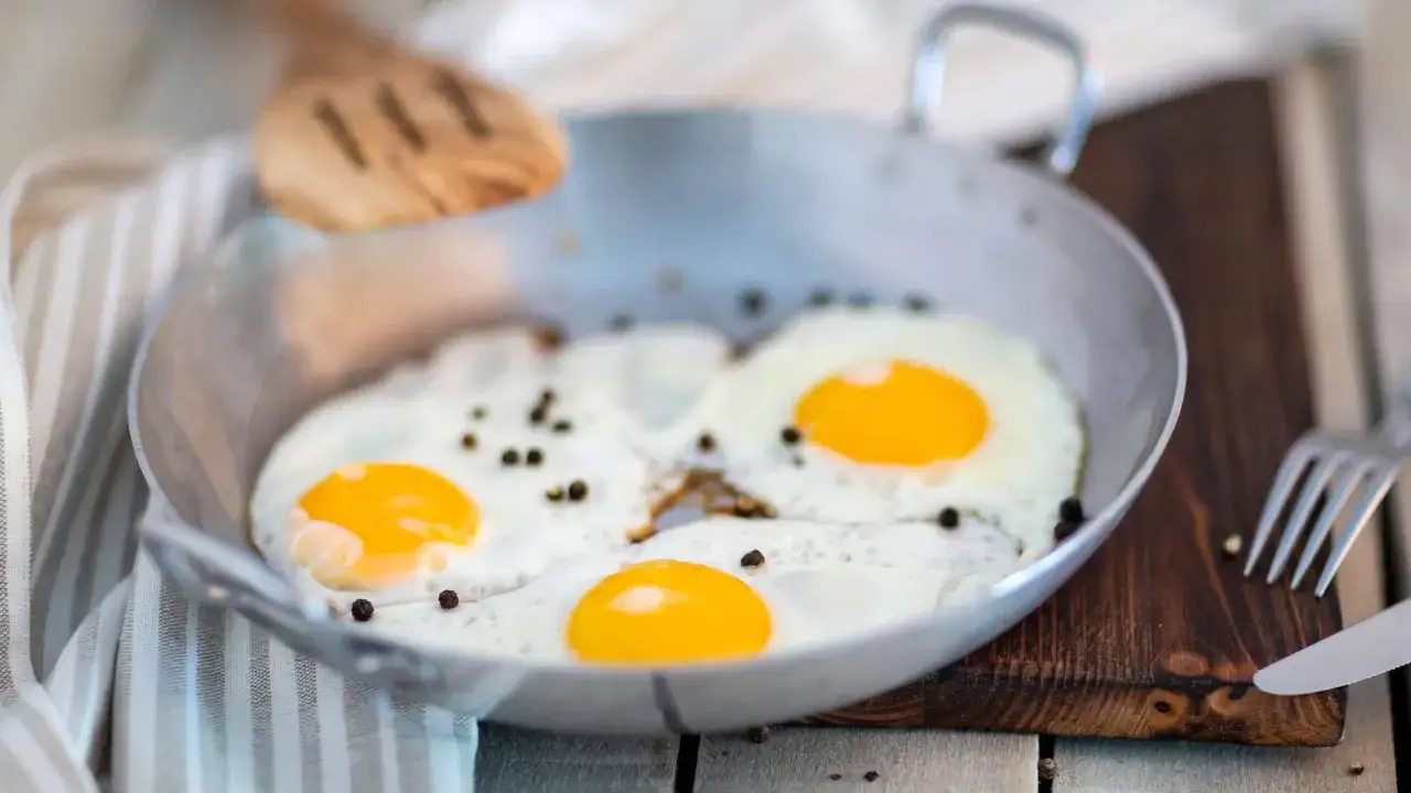 Perfektes Spiegelei Rezept: Drei goldgelbe Spiegeleier mit schwarzem Pfeffer in einer Pfanne, bereit zum Servieren.