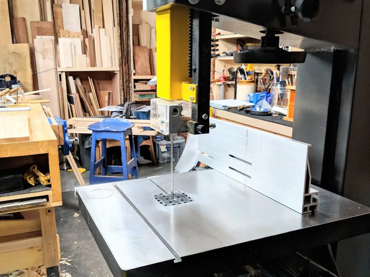 Dans un atelier, une scie &agrave; ruban est pr&ecirc;te &agrave; d&eacute;couper du bois. Un marteau repose &agrave; proximit&eacute;, attendant sa t&acirc;che.