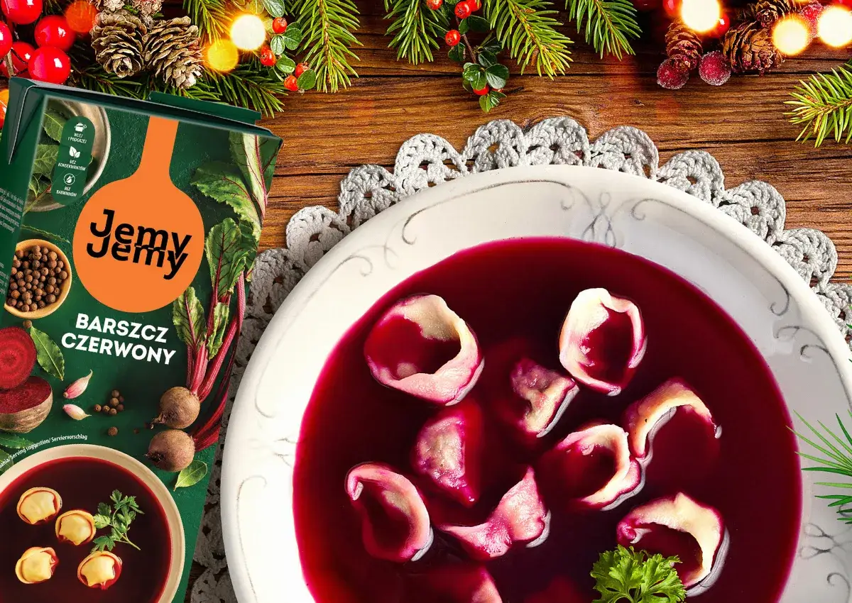 Aromaticzny barszcz czerwony z pasztecikiem, ozdobiony gałązkami choinki i jagódkami, gotowy na świąteczny stół.