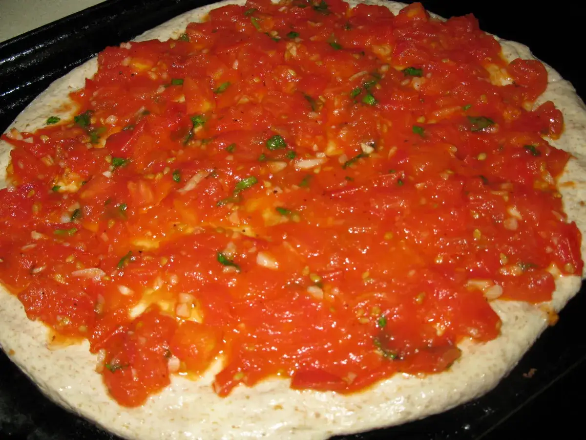 Frische, stückige Tomaten bedecken den Teig – die Basis für eine authentische, original italienische pizzasauce.