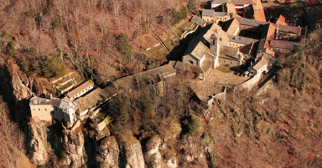 Il Santuario della Verna, un complesso monastico arroccato su uno sperone roccioso, immerso nel bosco autunnale. Un luogo di pace e spiritualità.
