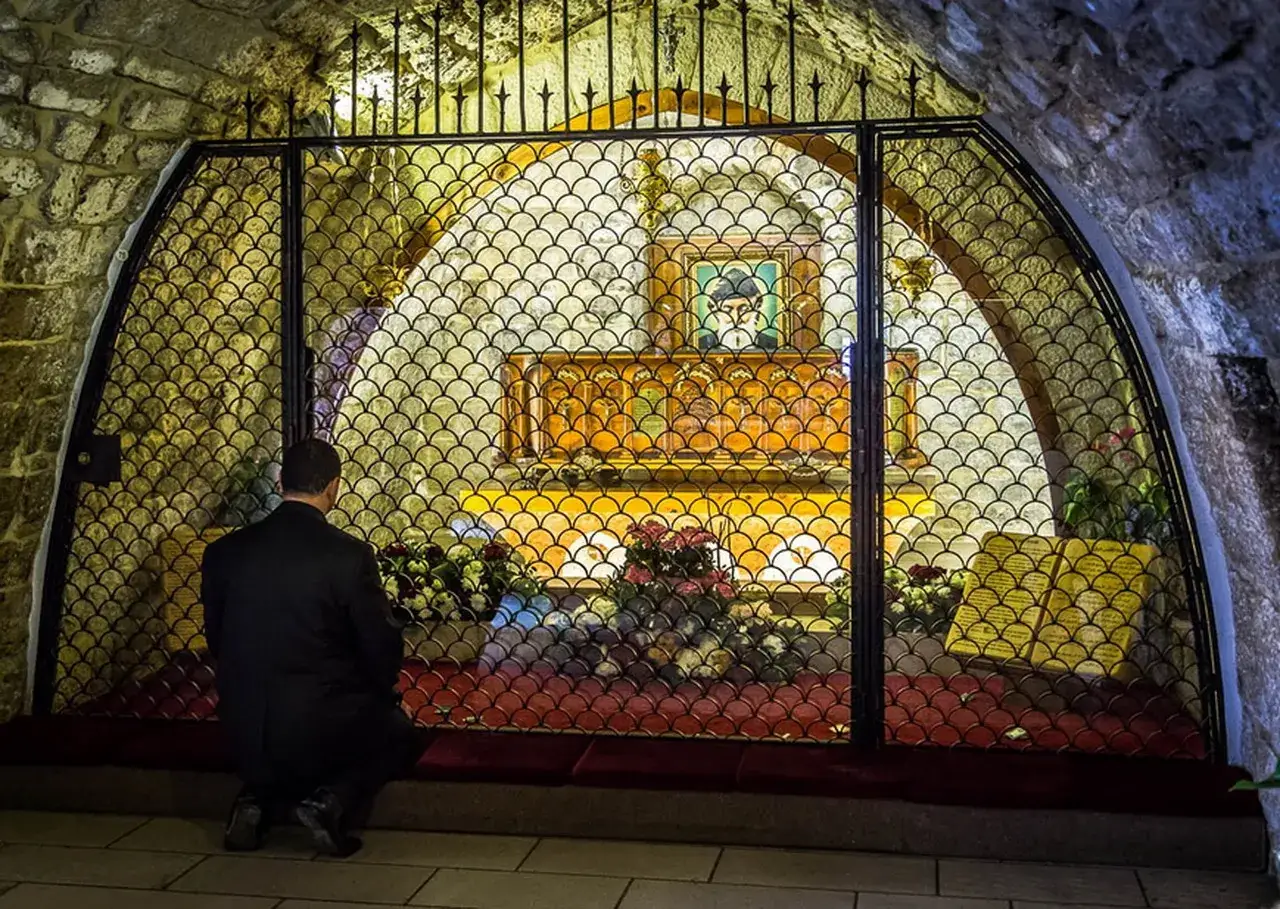 Mężczyzna klęczy przed relikwiarzem, szukając pocieszenia w przepowiedniach św. Charbela.