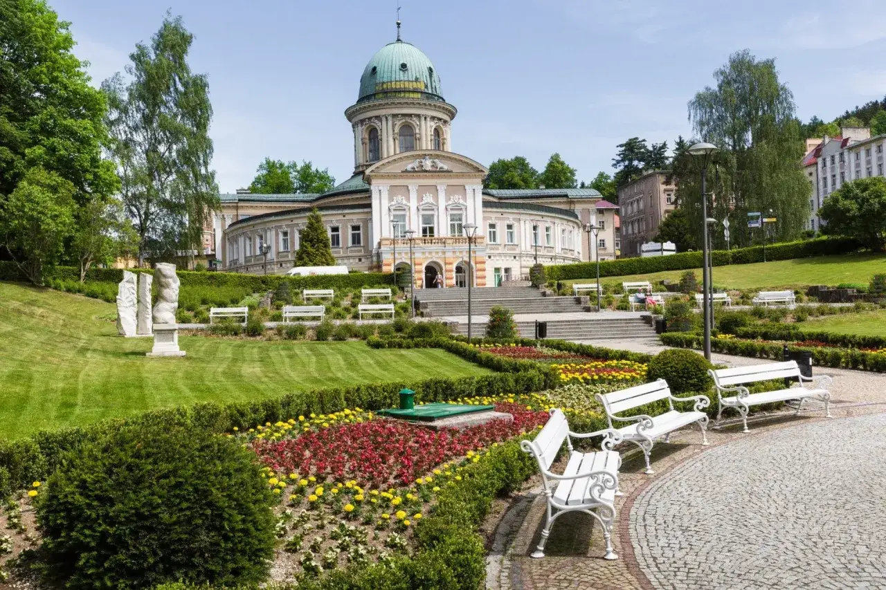 Piękny park zdrojowy z rzeźbami i klombami kwiatów. Zastanawiasz się, ile trzeba dopłacić do sanatorium?