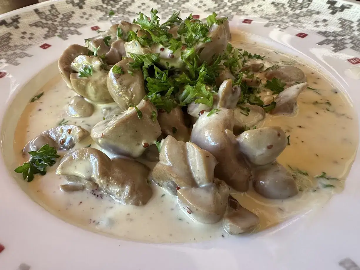 Délicieux rognon de veau en sauce crémeuse, garni de persil frais. Un plat savoureux prêt à être dégusté.