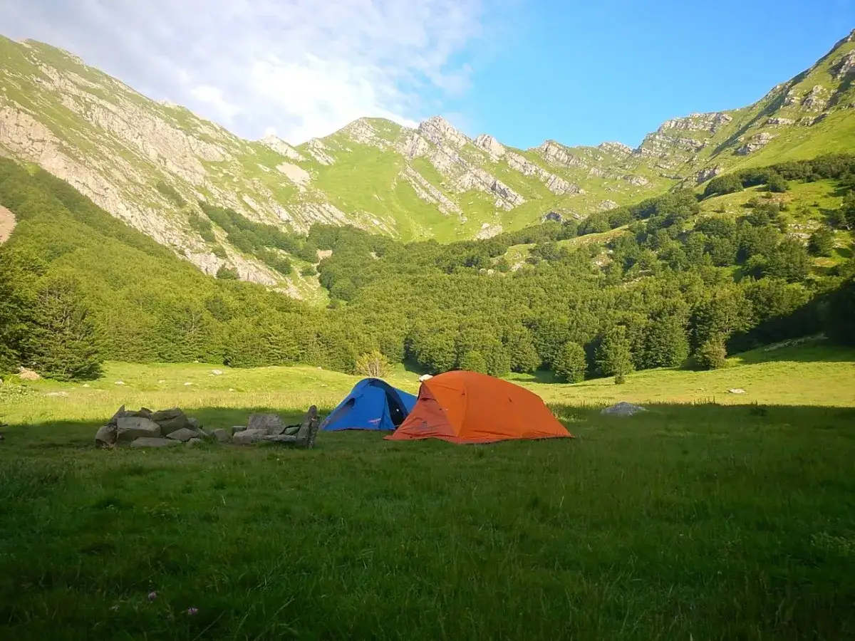 Tende da campeggio in un prato verde ai piedi di montagne boscose, vicino alle sorgenti del Secchia.
