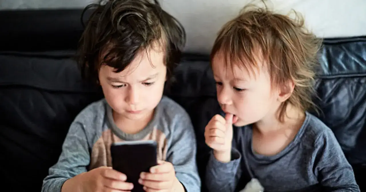 Dzieci oglądają bajkę na iPhonie, korzystając z funkcji Family Link.