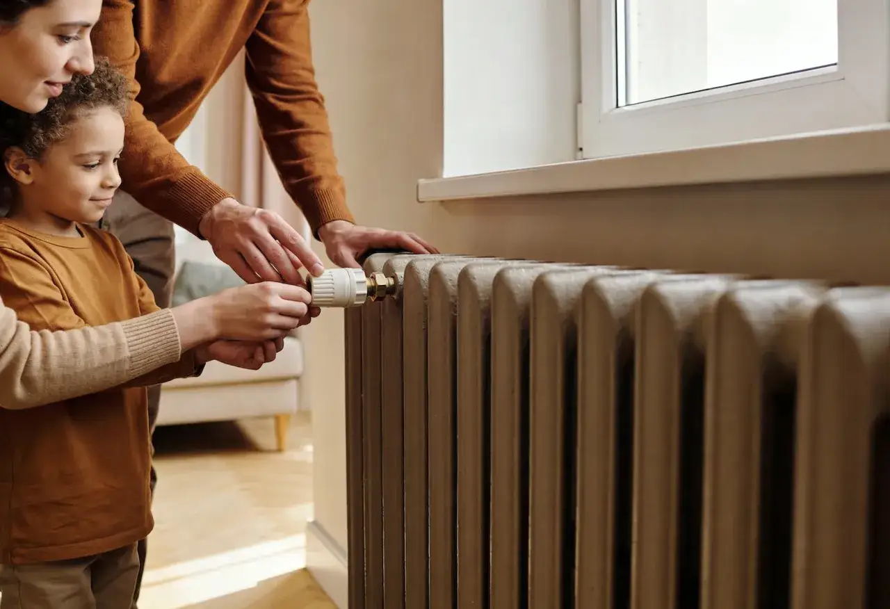 Familia ajustando el termostato de la calefacci&oacute;n central en comunidades de vecinos para un hogar c&aacute;lido y confortable.