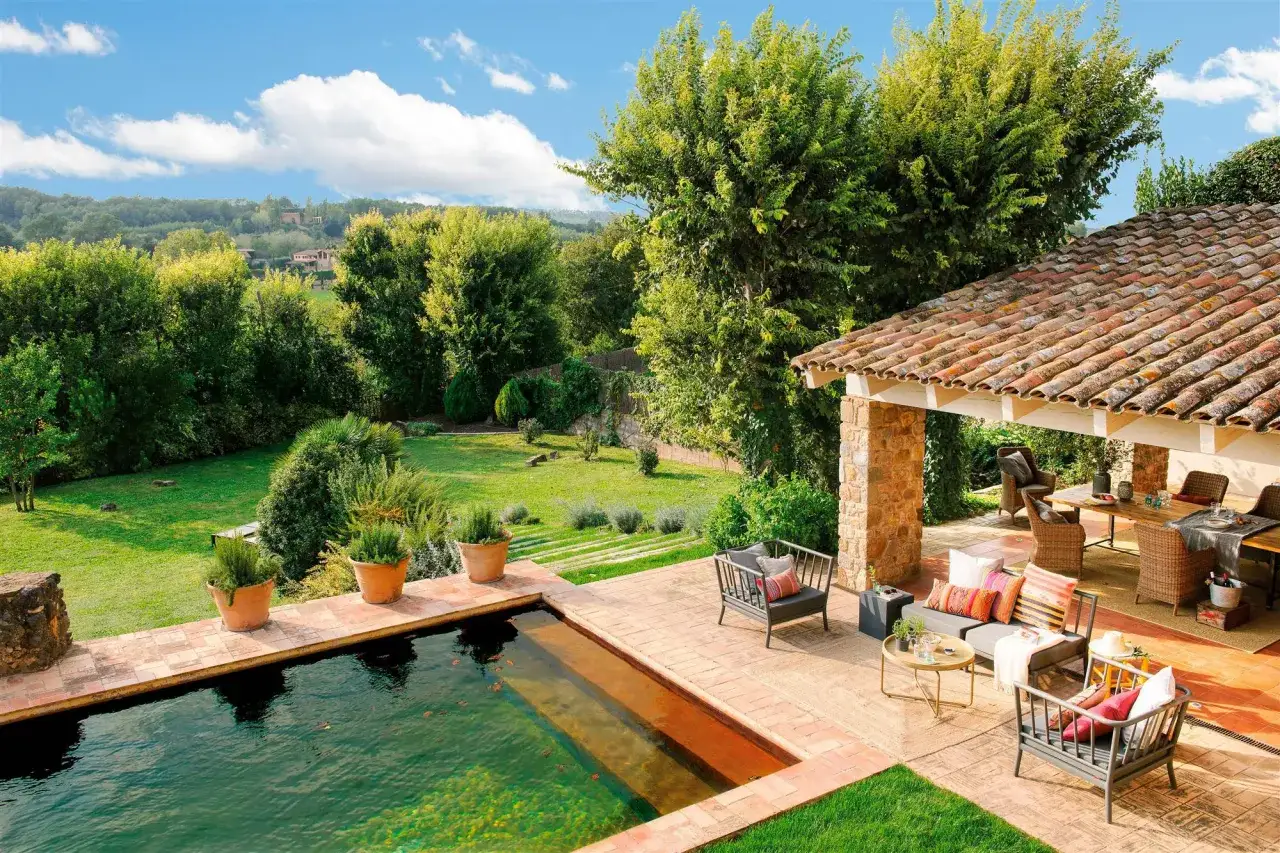 Un idílico jardín con piscina y un porche acogedor, perfecto para disfrutar del sol y la naturaleza.