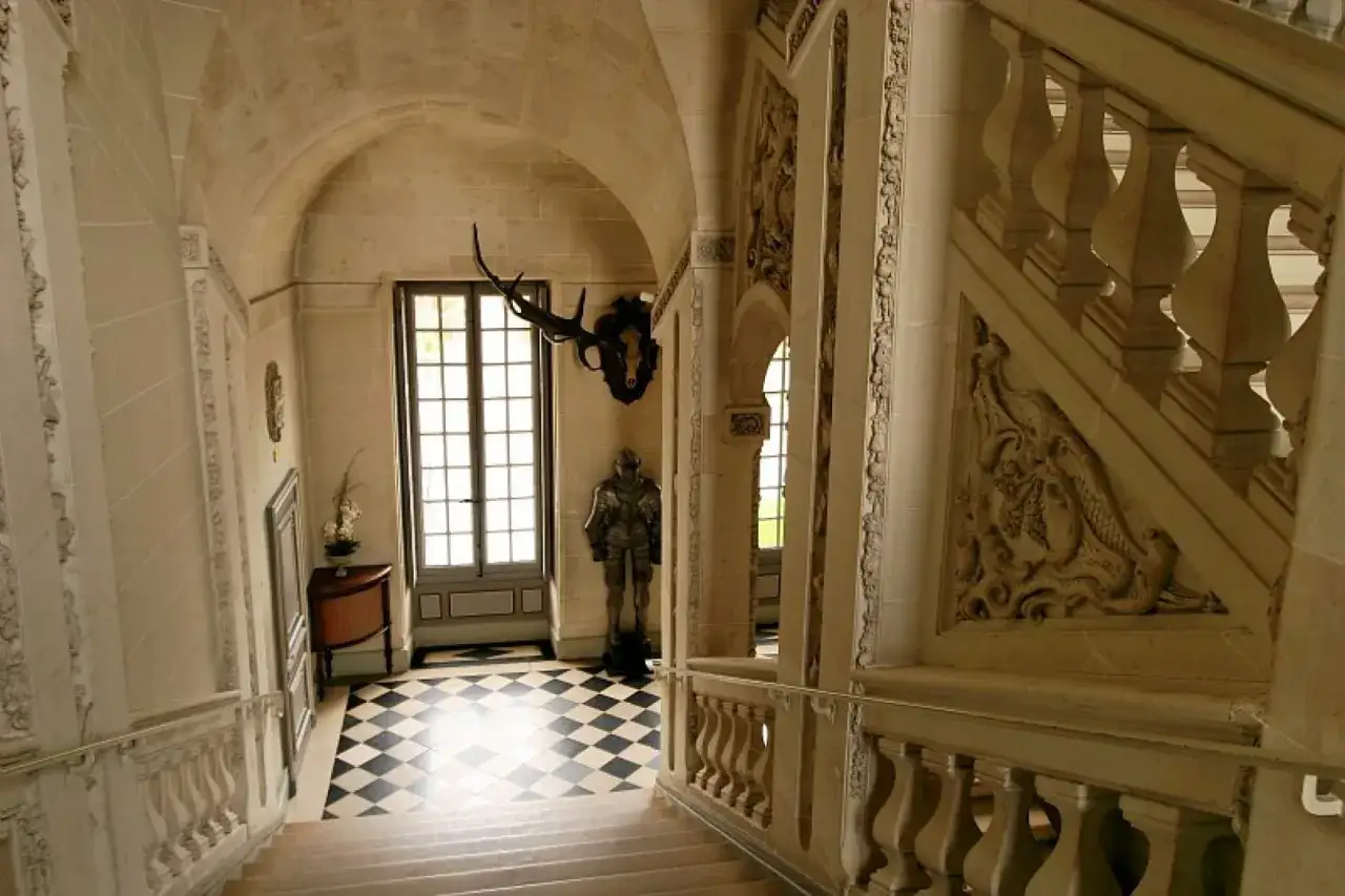 Escalier d'un ch&acirc;teau de la Loire, avec un damier noir et blanc, une armure et des bois de cerf, digne d'une aventure de Tintin.