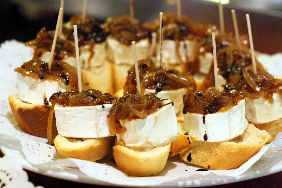 Delicious goat cheese toast appetizers, topped with caramelized onions and a balsamic glaze, are ready to be enjoyed.