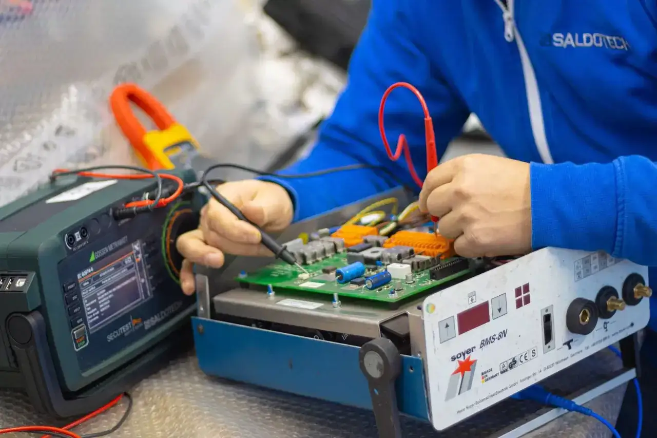 Tecnico effettua la riparazione di saldatrici, testando i componenti elettronici con strumenti di precisione.