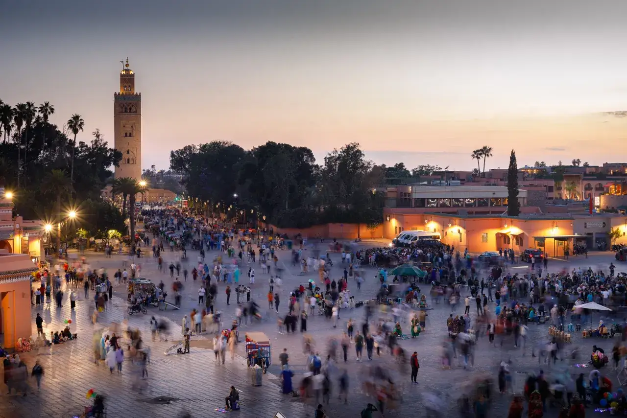 Plaza de Jemaa el-Fna en Marrakech al atardecer. Una multitud se mueve bajo la Koutoubia, ideal para un plan de Marrakech en 3 d&iacute;as.