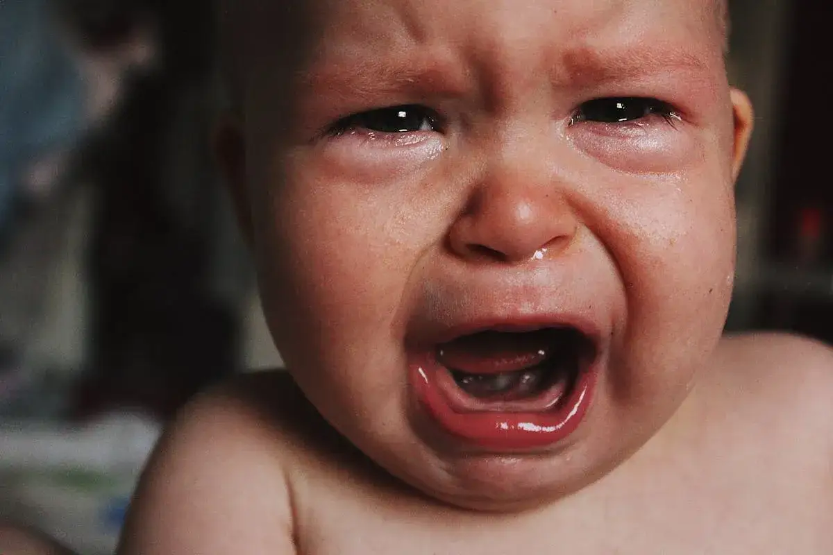 Un bimbo piange disperato, con lacrime che rigano il viso. Forse &egrave; stanco, o ha fame, ecco perch&eacute; i bambini si sdraiano per terra.