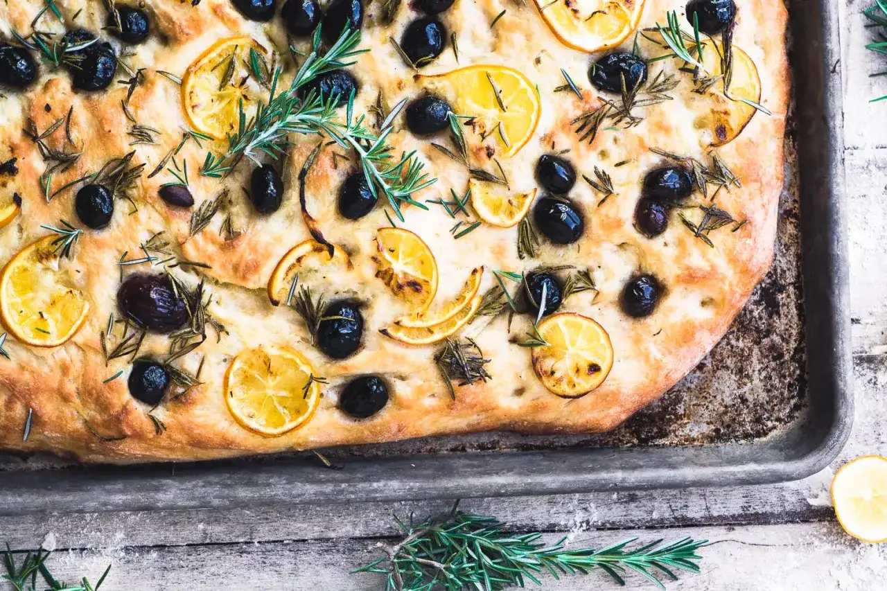 En gyllene focaccia med oliver, citronskivor och rosmarin. Ett perfekt recept för hembakad focaccia.