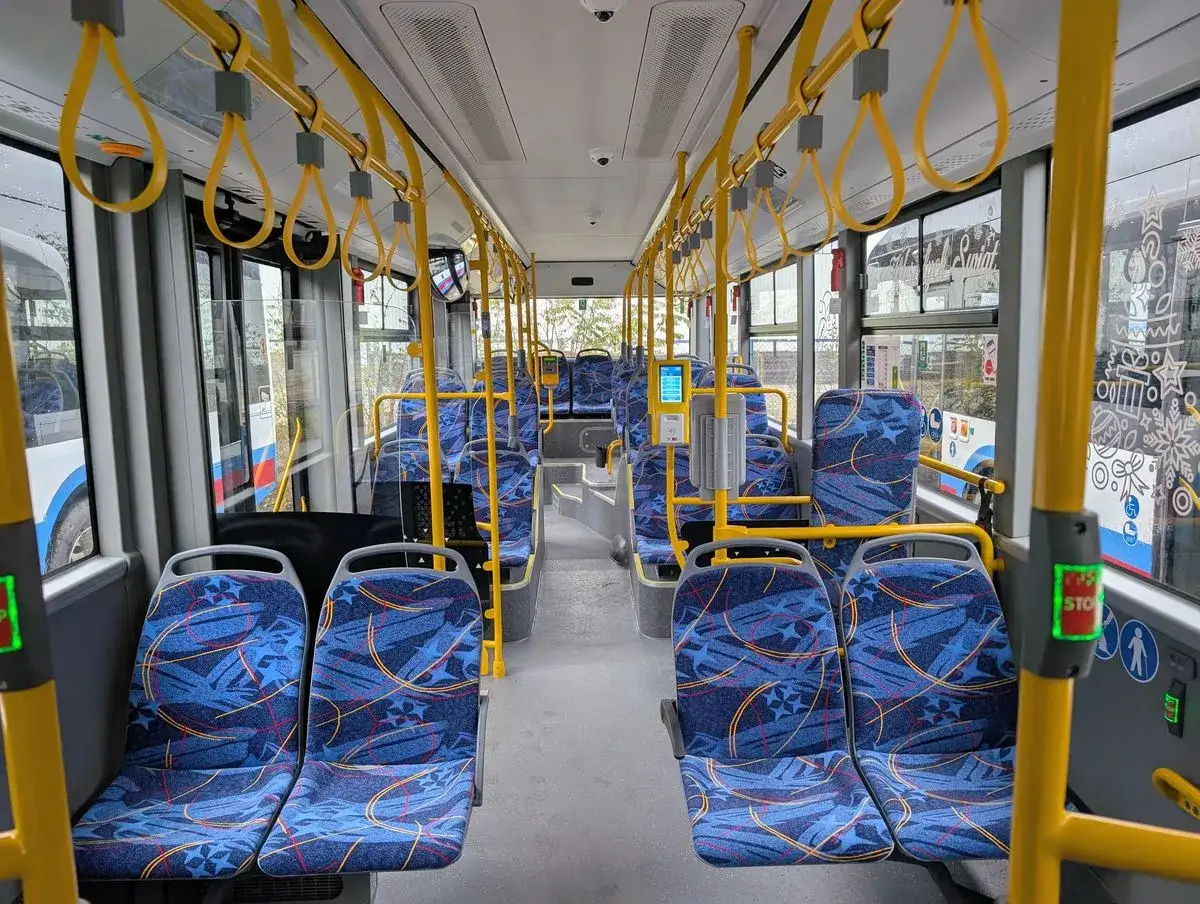 Wnętrze autobusu Yutong z niebieskimi siedzeniami i żółtymi uchwytami. Pusto, gotowe na pasażerów.