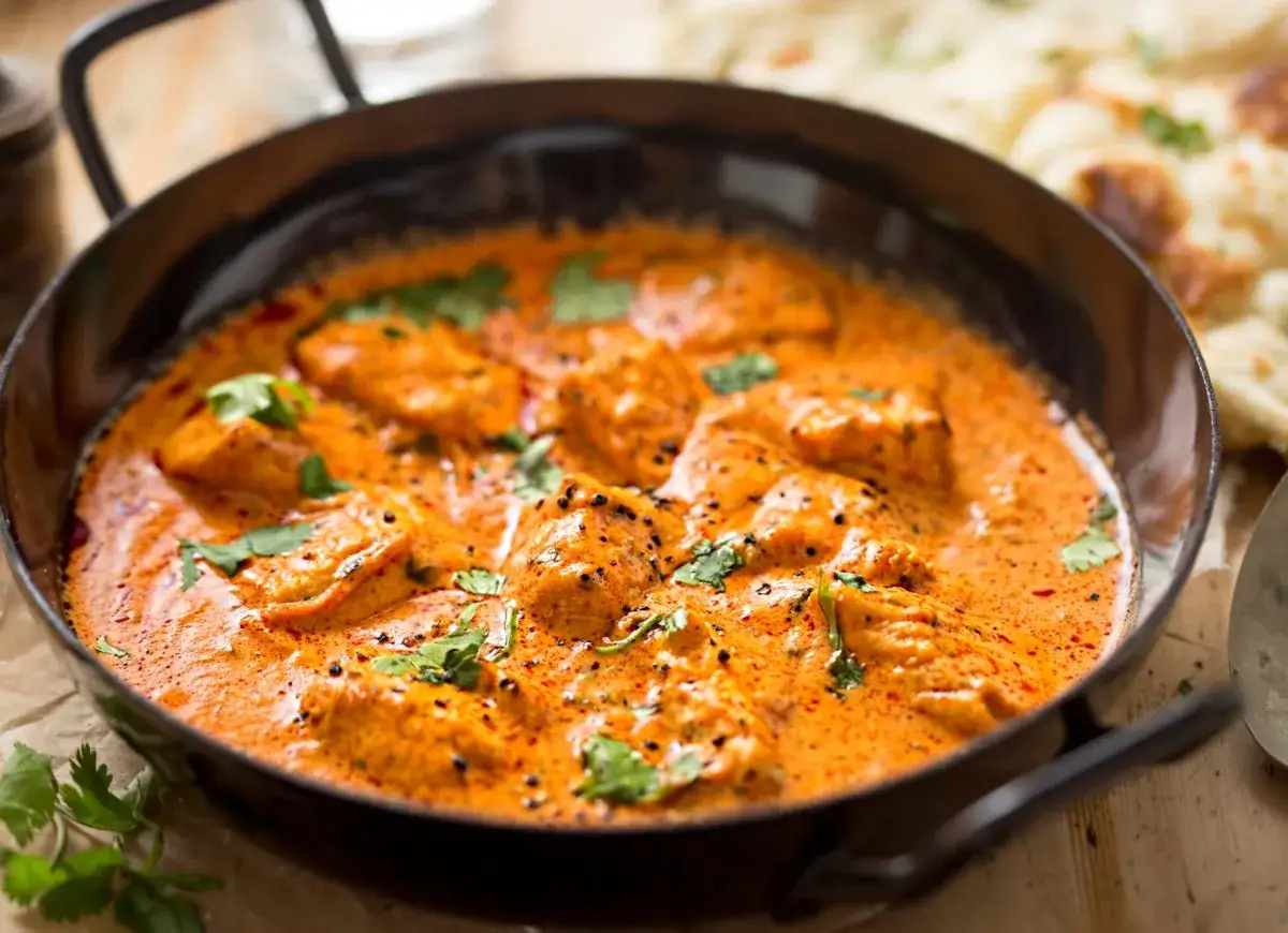 Pyszny kurczak w sosie curry, idealny na prosty obiad. Aromatyczne kawałki kurczaka w kremowym, pomarańczowym sosie, posypane świeżą kolendrą.