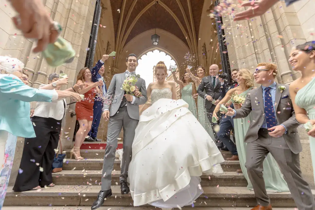 Un couple de mari&eacute;s rayonnant descend les marches sous une pluie de confettis. Une sc&egrave;ne de musique sortie mariage dynamique et joyeuse.