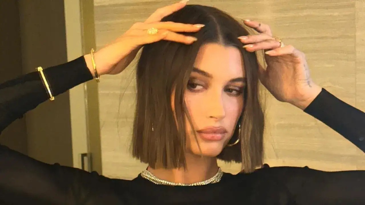 Modello con capelli castani, lisci e pochi, indossa un abito nero e gioielli d'oro.