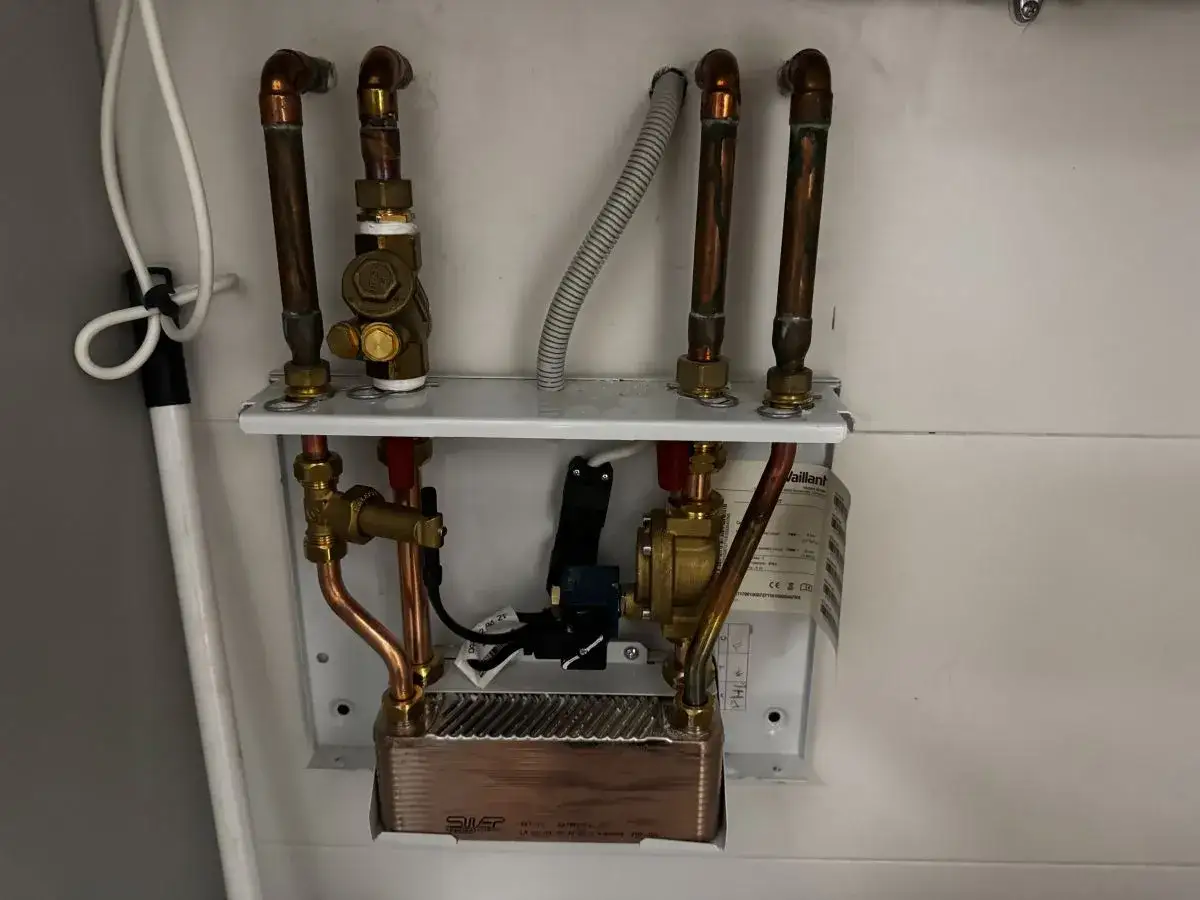 Instrukcja jak dolać wody do pieca Vaillant Ecotec Plus. Widoczne zawory i rury miedziane.