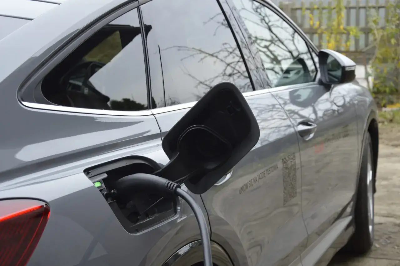 Szary Audi Q4 e-tron podłączony do ładowania. Sprawdź jego imponujący zasięg i um&oacute;w się na jazdę testową!