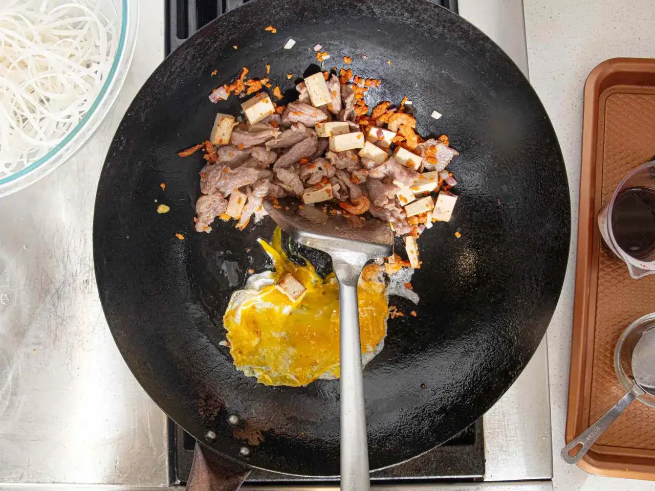 Na patelni wok smaży się jajko, mięso, tofu i krewetki. Tak powstaje pyszny pad thai co to za danie?