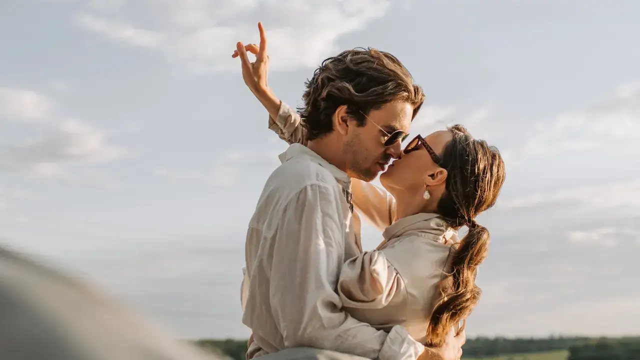 Pareja besándose apasionadamente bajo el cielo. Un momento que inspira frases de besos inolvidables.