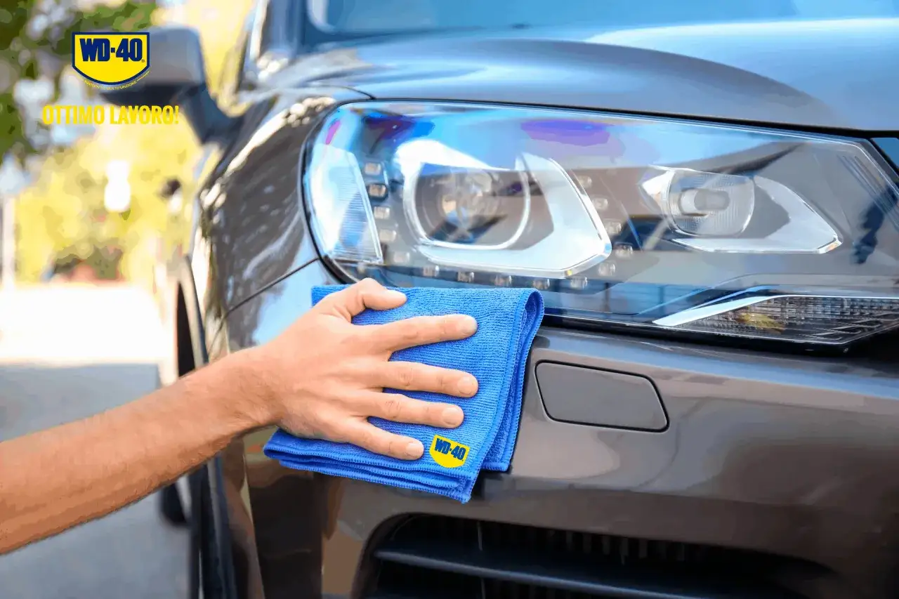 Mano che pulisce il faro di un'auto con un panno blu. Scopri come pulire i fari della macchina per un risultato brillante.