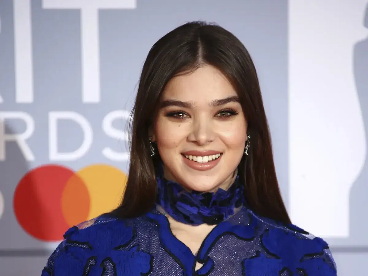 Hailee Steinfeld sonríe con un maquillaje impecable que complementa su vestido azul.