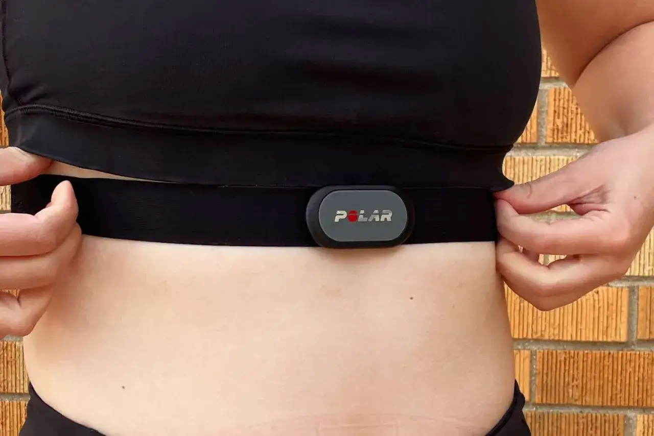 A person adjusts a Polar heart rate monitor chest strap, a common way how heart rate monitors work by detecting electrical signals from the heart.