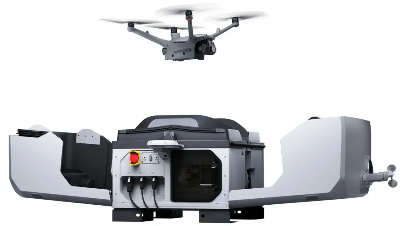 A grey drone hovers above a futuristic, open-sided charging station. This advanced system is designed for autonomous security drones, ready for deployment.