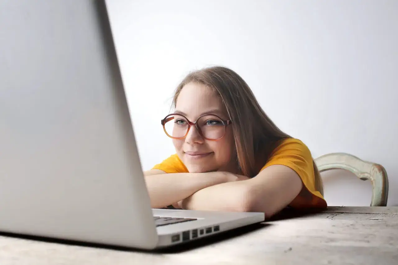 Uśmiechnięta osoba oglądająca serial na laptopie z notatkami, uczy się angielskiego