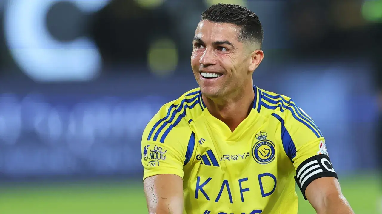 Uśmiechnięty Cristiano Ronaldo w żółtej koszulce Al Nassr. Zastanawiasz się, ile zarabia Ronaldo na minutę?