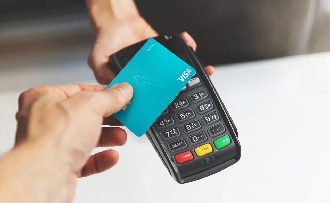 Tarjeta débito BBVA acercándose a un terminal de pago.
